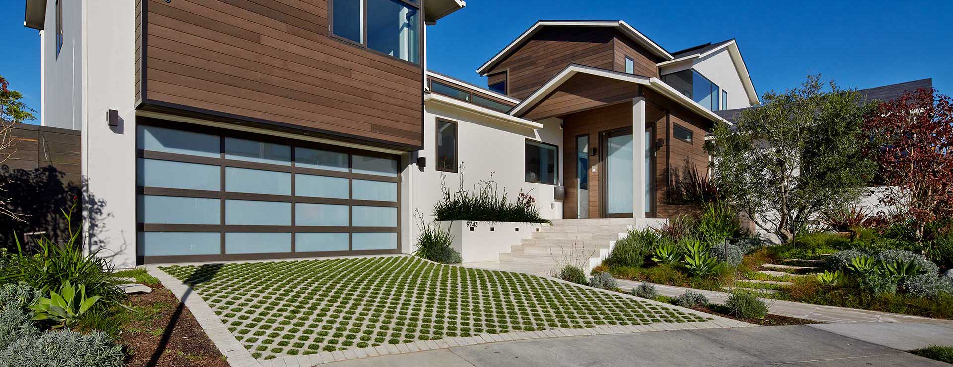 exterior of modern home with paneled garage door and driveway with circular patterned grass patches