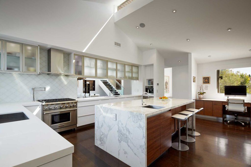 modern kitchen with white and grey cabinetry and white marble island with sink and stools