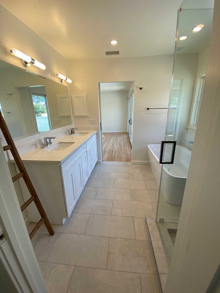 bathroom with vanity featuring two sinks a glass door shower and a bathtub