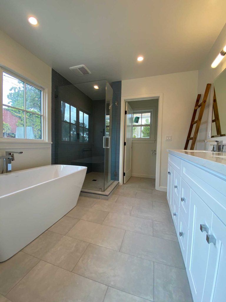 bathroom with white tub and shower with glass doors