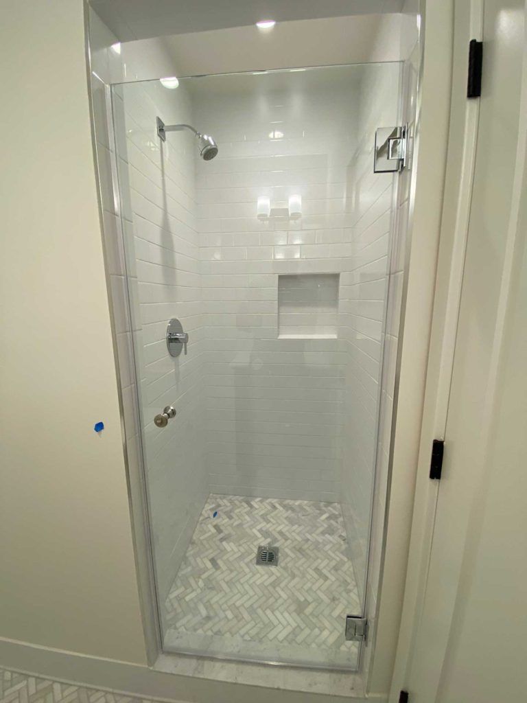 glass door shower with white tiles