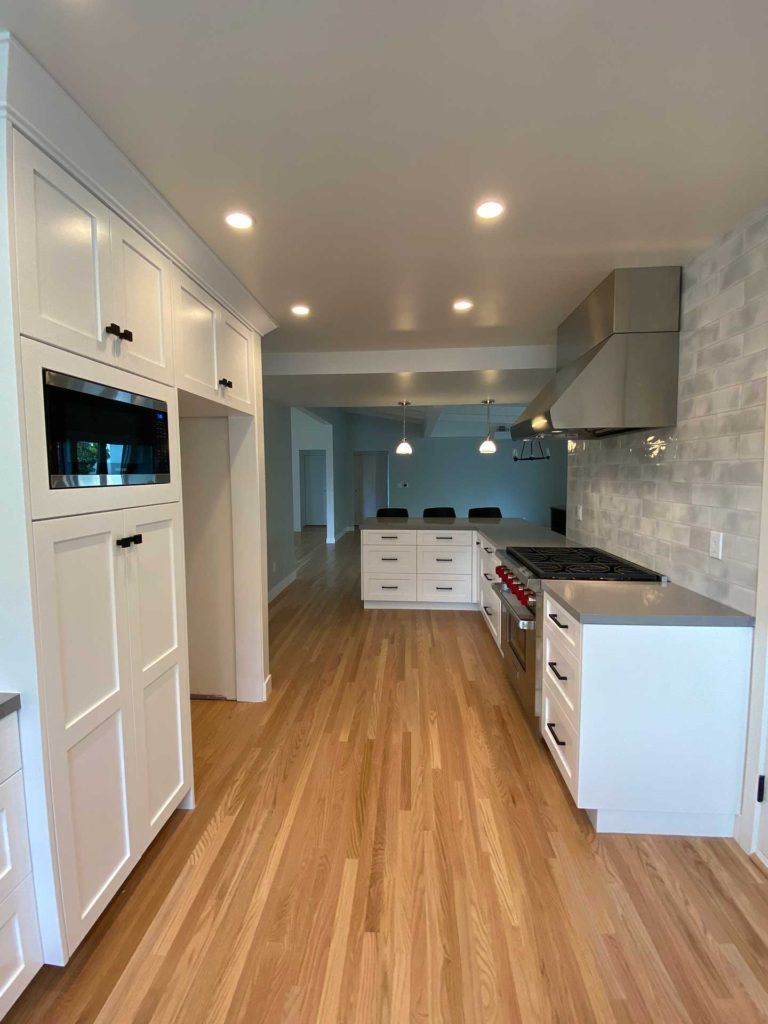 kitchen with white cabinetry featuring black handles and living area in the background