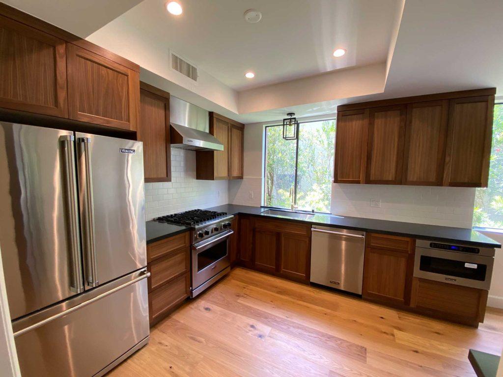 kitchen with brown cabinetry wood floors and stainless steel fridge