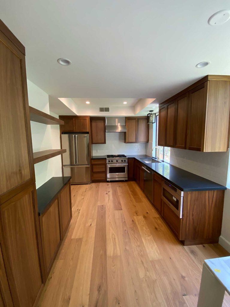 kitchen with brown cabinetry wood floors and stainless steel fridge