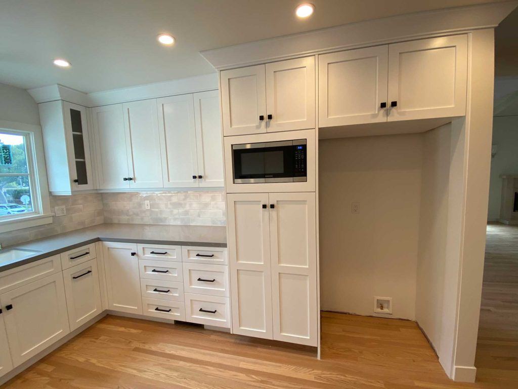 kitchen with white cabinetry and microwave embedded in wall