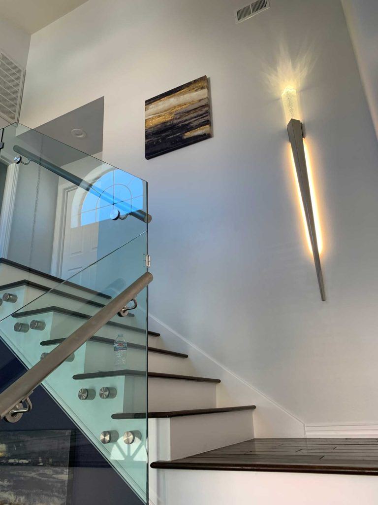 staircase with dark brown floors glass paneling and steel railings